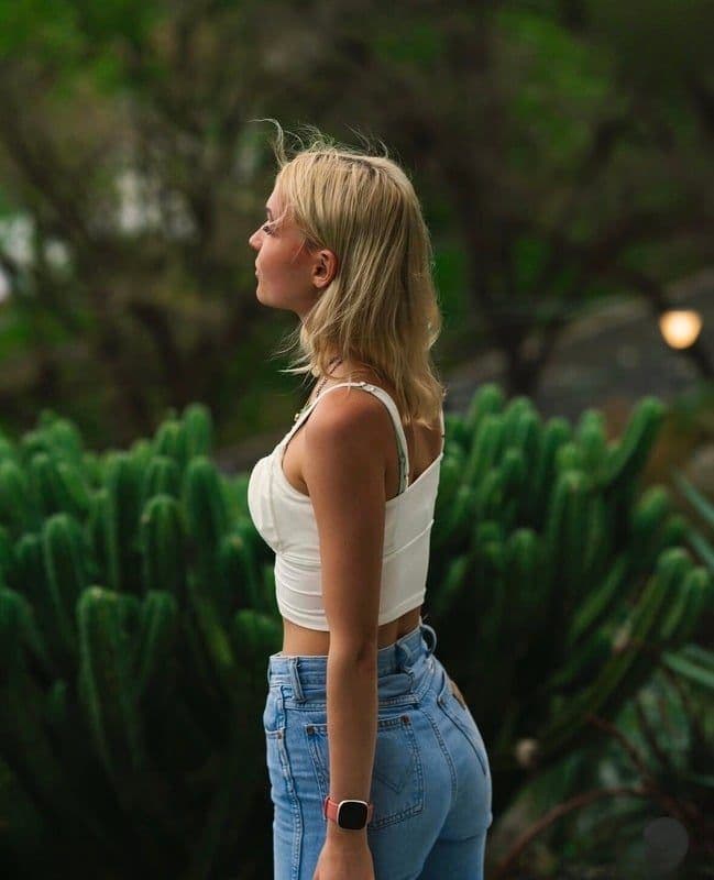 Ane Eline Larsen in profile, wearing a white top, against greenery